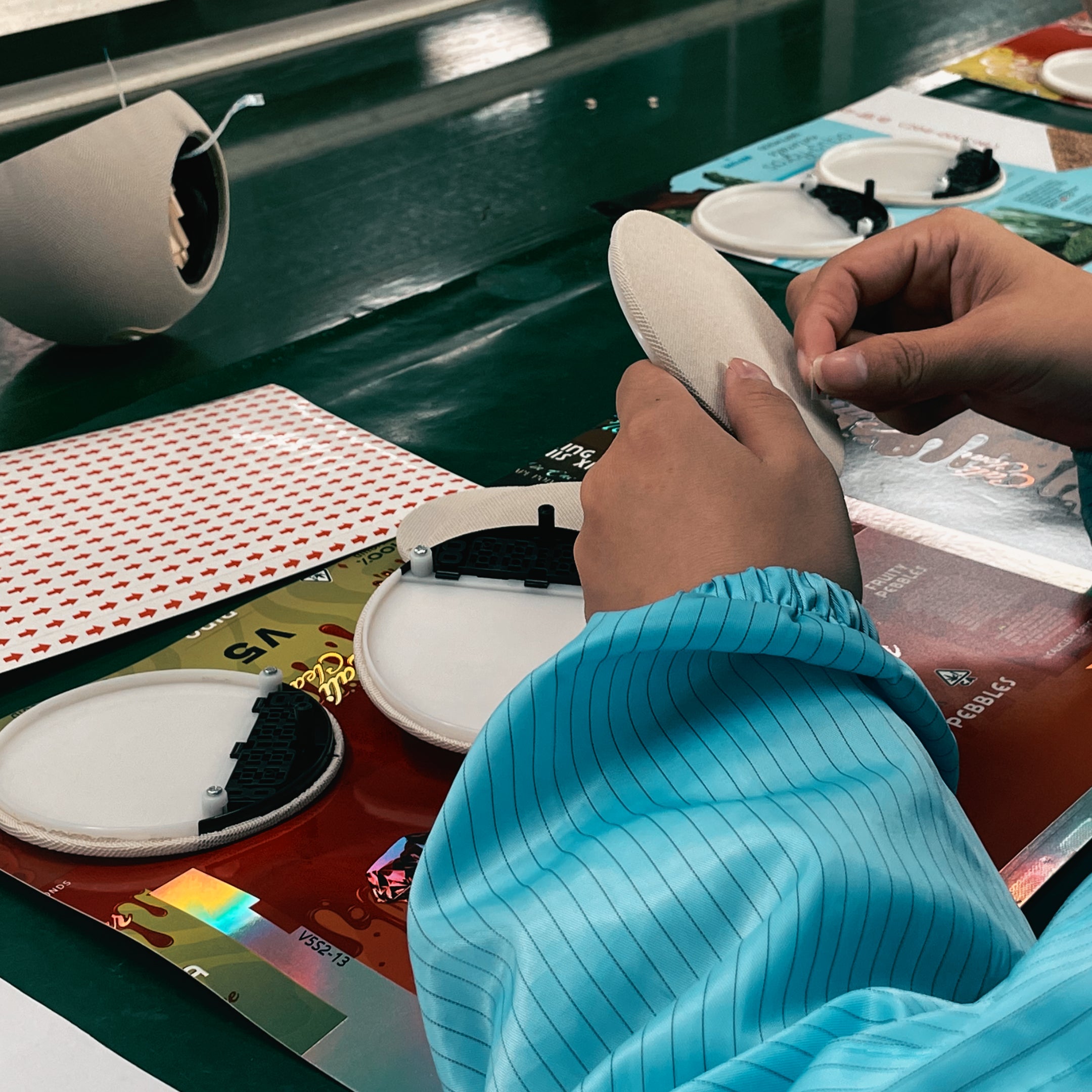 A quality control specialist wearing blue gloves carefully inspecting the white product shell to ensure a flawless surface finish.