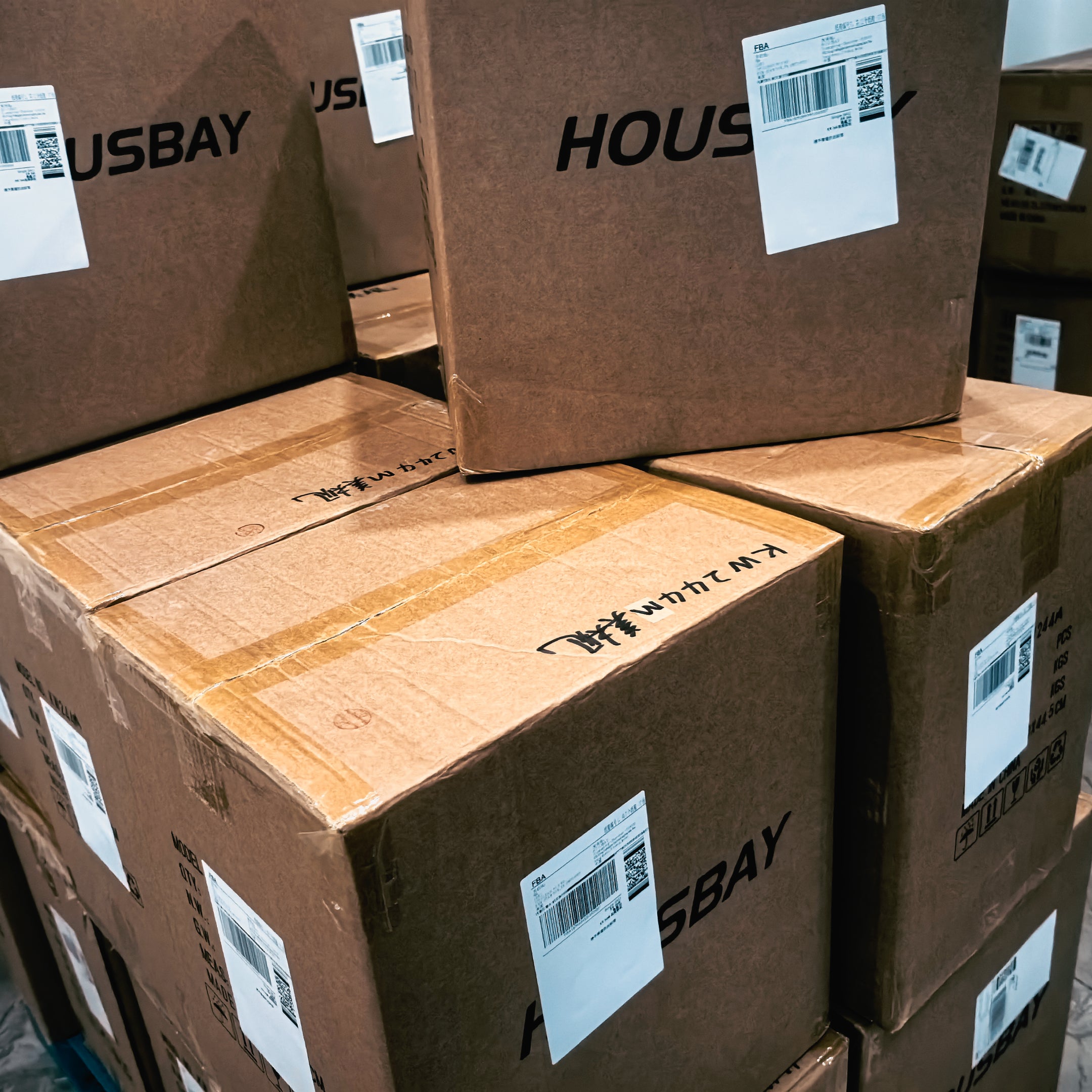 Neatly stacked brown shipping cartons printed with the HOUSBAY brand logo, ready for global distribution.
