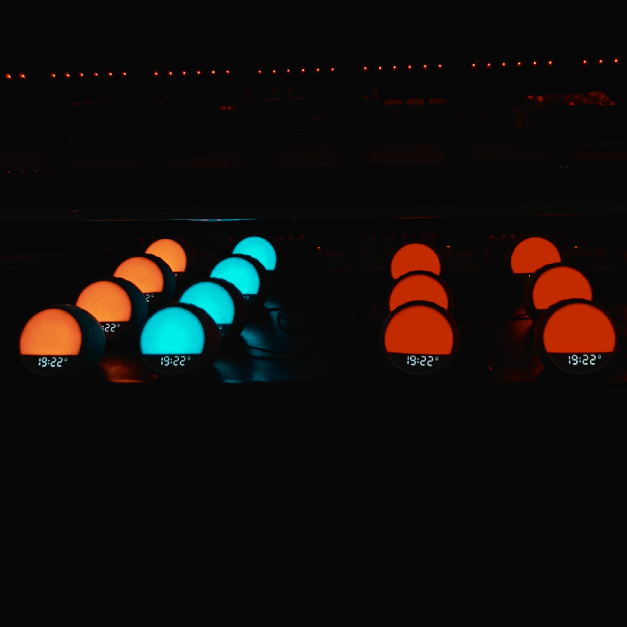 Multiple HOUSBAY MINI units undergoing aging tests in a dark room environment, displaying various blue and orange light effects.