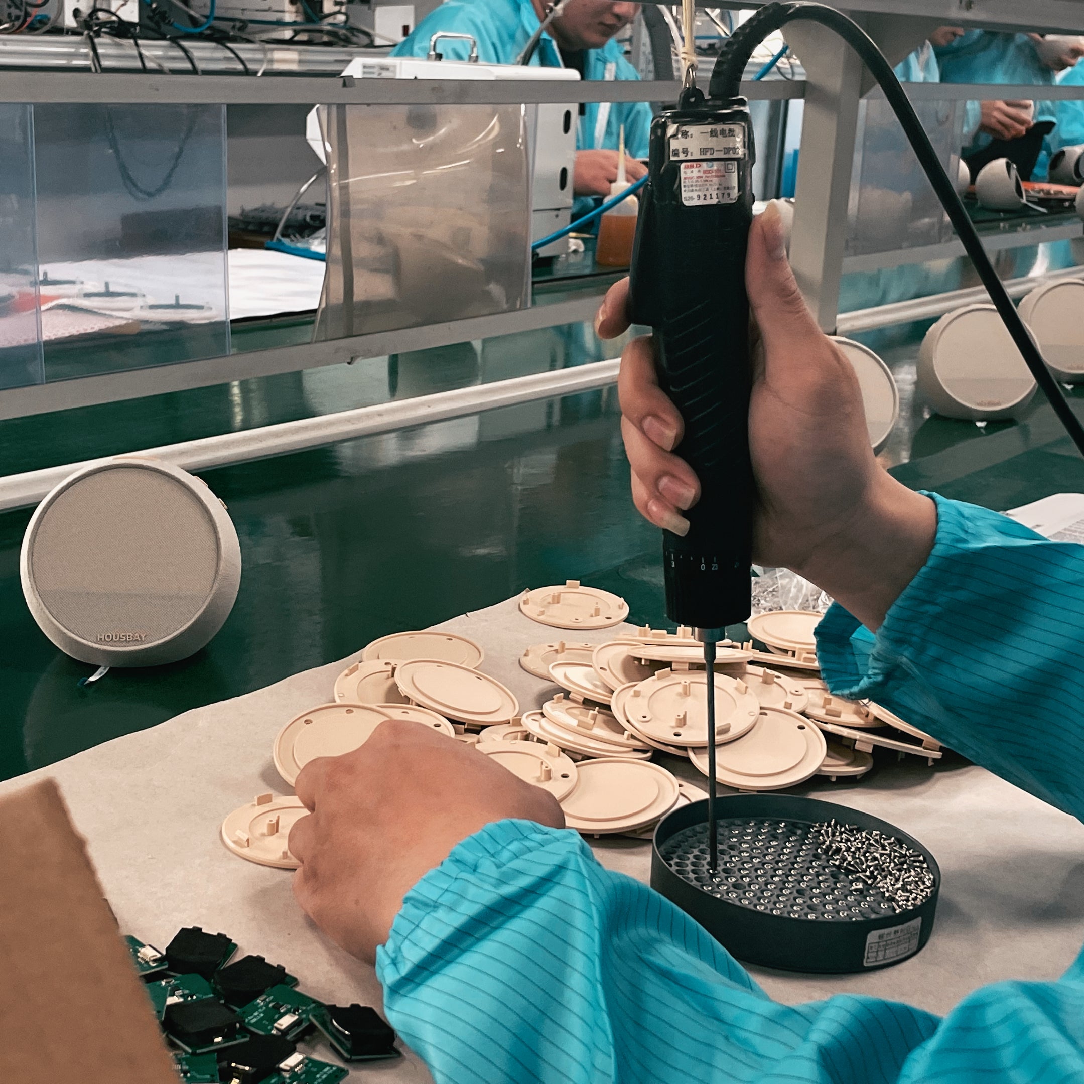 A technician using an electric screwdriver to assemble internal electronic components and circuit boards into the product base.
